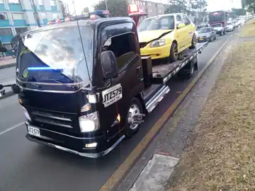 Servicio real de grúa transportando un automóvil amarillo